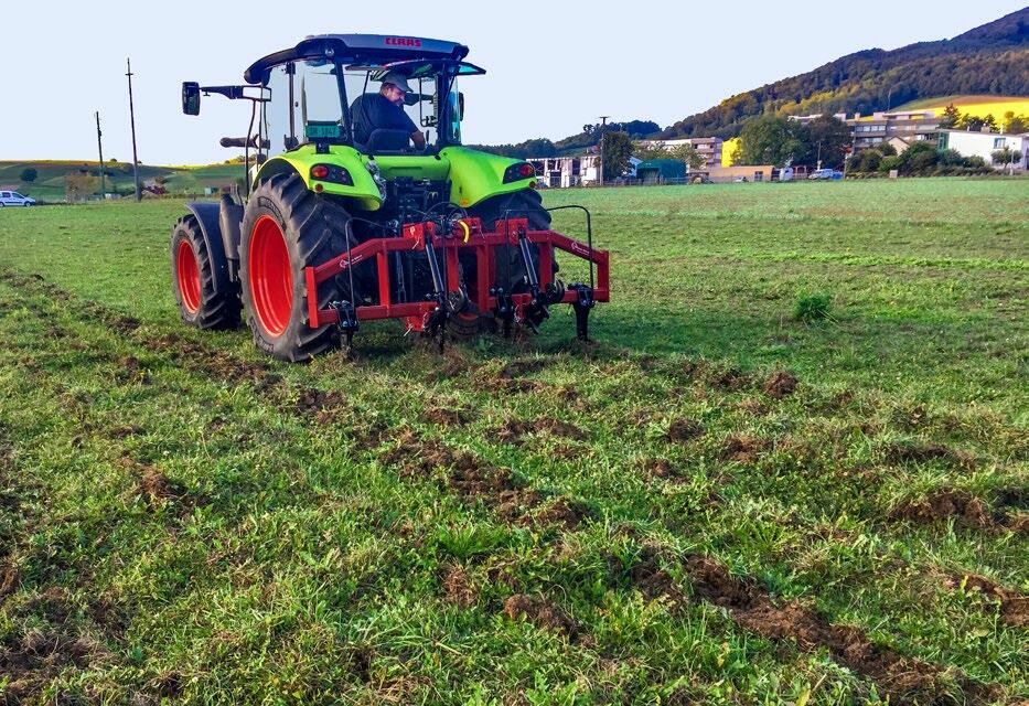 Untergrundlockerung in einer Kunstwiese mit einem Gerät mit geraden Zinken.