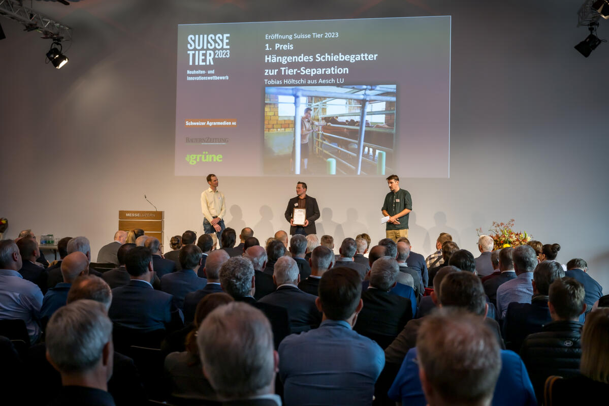 Tobias Höltschi (Mitte) holt den ersten Platz der bäuerlichen Innovationen. Links Jurypräsident Christian Galliker, rechts Moderator Livio Janett.