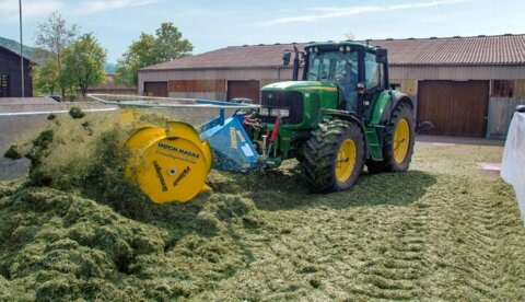 Tracteur de tassage avec répartiteur d’ensilage d’herbe sur le silo-tranchée