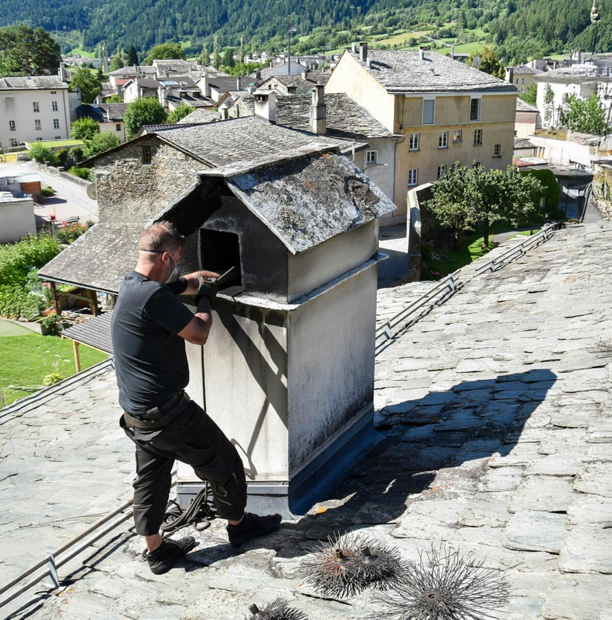 Über den Dächern des Wakker-Dorfes Poschiavo: Der Kaminfegermitarbeiter Luca Tuena bei der Arbeit auf dem Hausdach, um von dort aus den Kamin zu kehren.